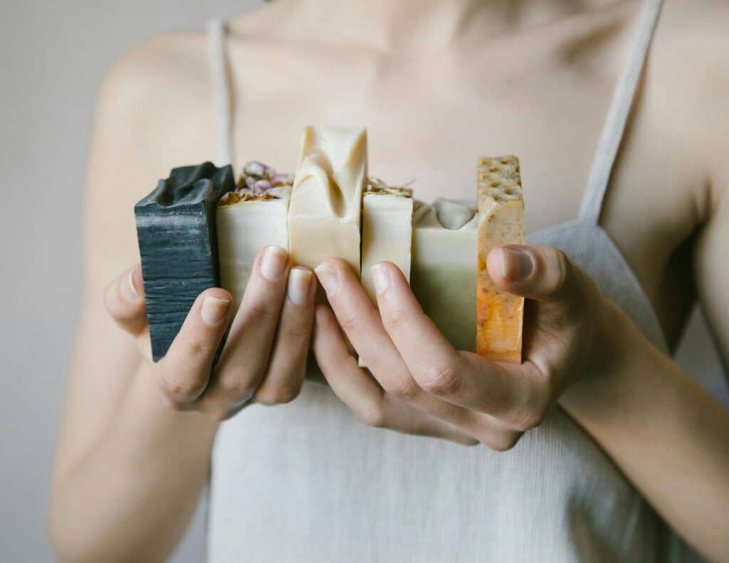 Hands holding a natural soap bar with dried herbs inside