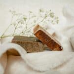 Two handmade soap bars with a delicate white flower on a soft fabric