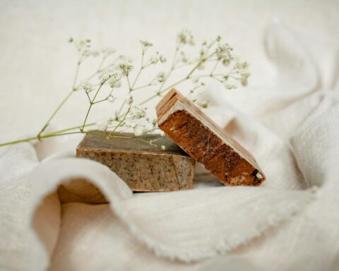 Two handmade soap bars with a delicate white flower on a soft fabric