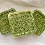 Three green square soap bars with “100% HAND MADE” stamped on top